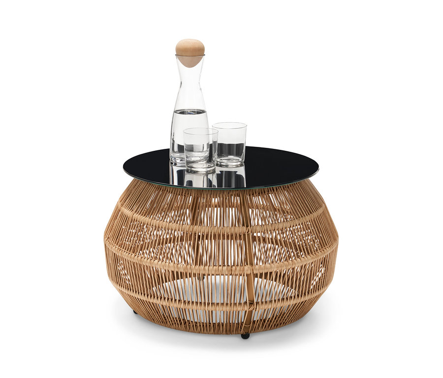 Auf einem Design-Beistelltisch mit Polyrattangeflecht stehen eine Karaffe Wasser und zwei Gläser.
