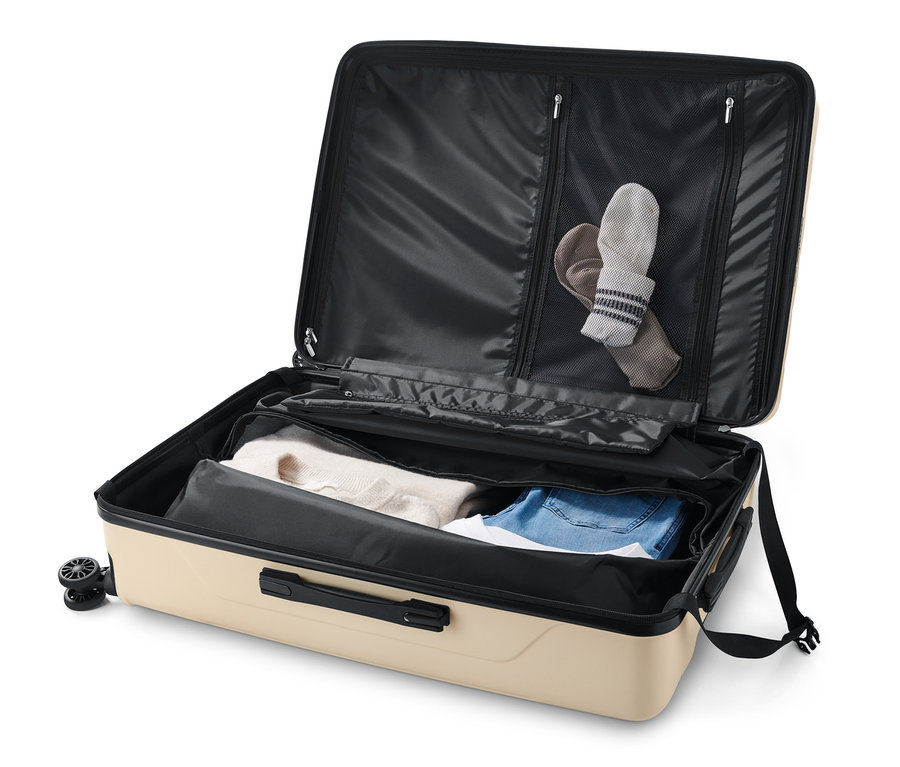 Geöffneter, grosser Hartschalen-Koffer mit recyceltem Material in Beige, gefüllt mit Kleidung und Socken.