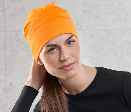 Frau sitzt und trägt eine neonorange Thermomütze.