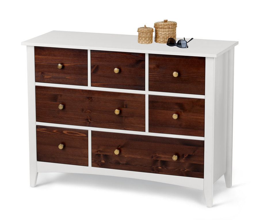 Kommode mit sieben Schubladen aus dunklem Holz mit weißem Rahmen, darauf zwei geflochtene Körbe und eine Sonnenbrille.