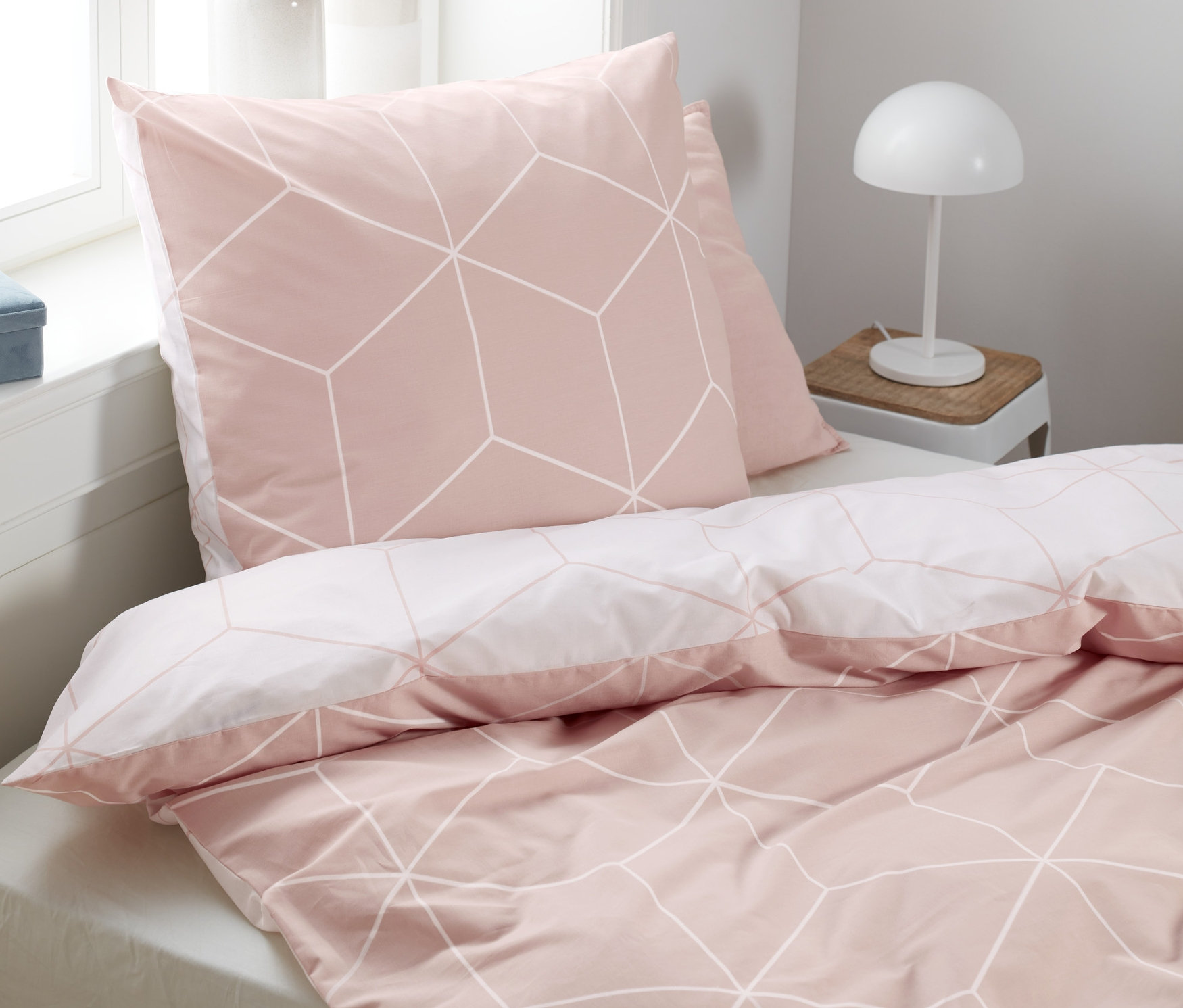 Auf einem Bett liegt Renforcé-Bettwäsche mit geometrischem Muster.