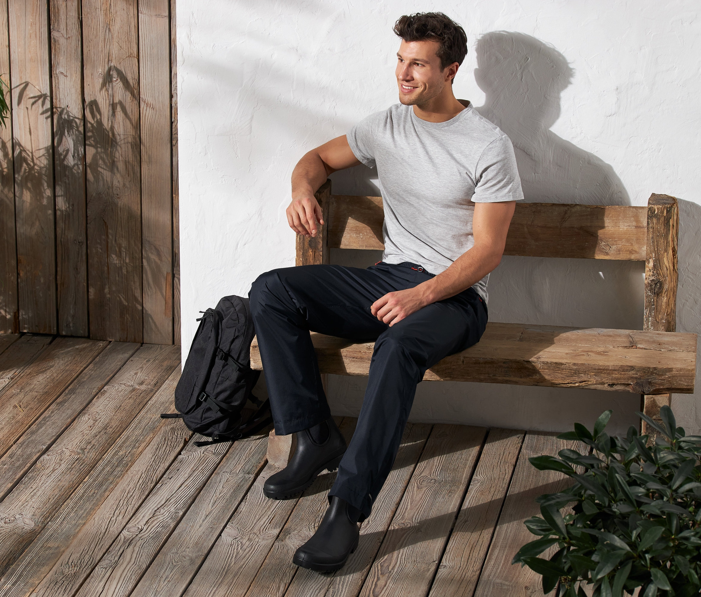 Mann sitzt auf einer Bank und trägt eine Unisex-Regenhose.