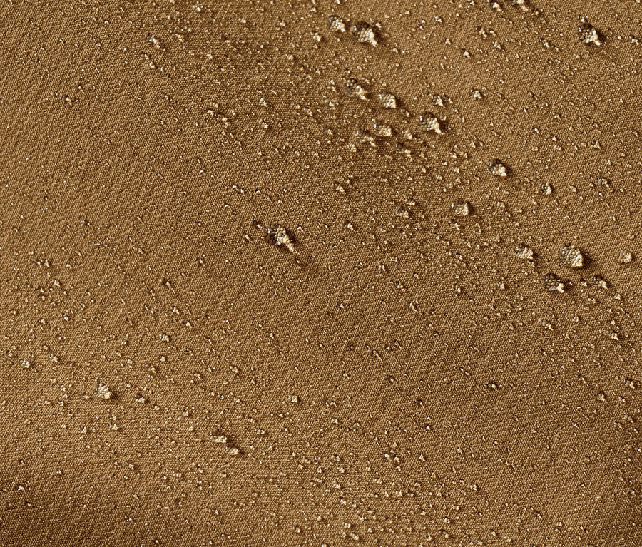 Nahaufnahme einer Softshell-Hose in Braun mit Wassertropfen.