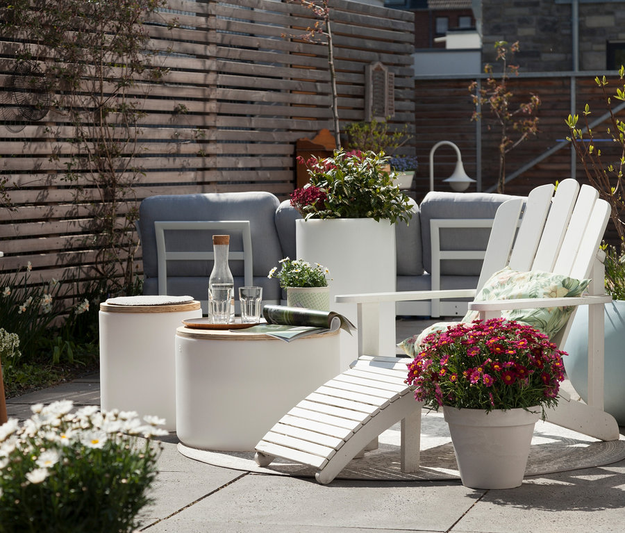 Außenbereich mit weißen Gartenmöbeln und Blumen in Töpfen, darunter eine 8 seasons design LED-Leuchte.