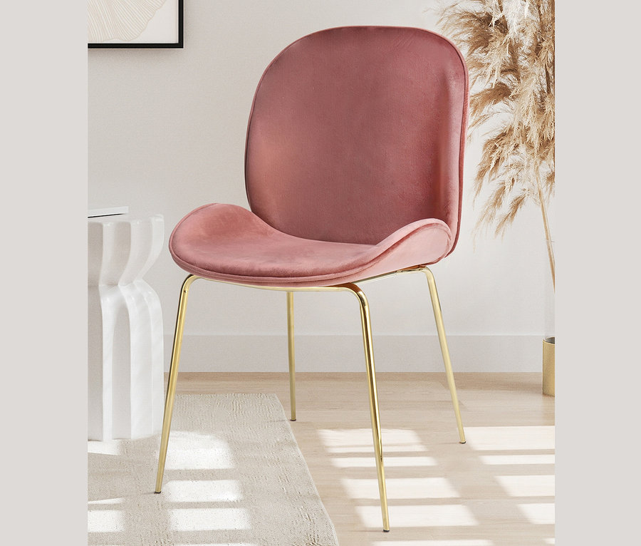 Ein altrosa Kayoom »Charlize« Stuhl mit goldenen Beinen steht auf einem beigen Teppich.