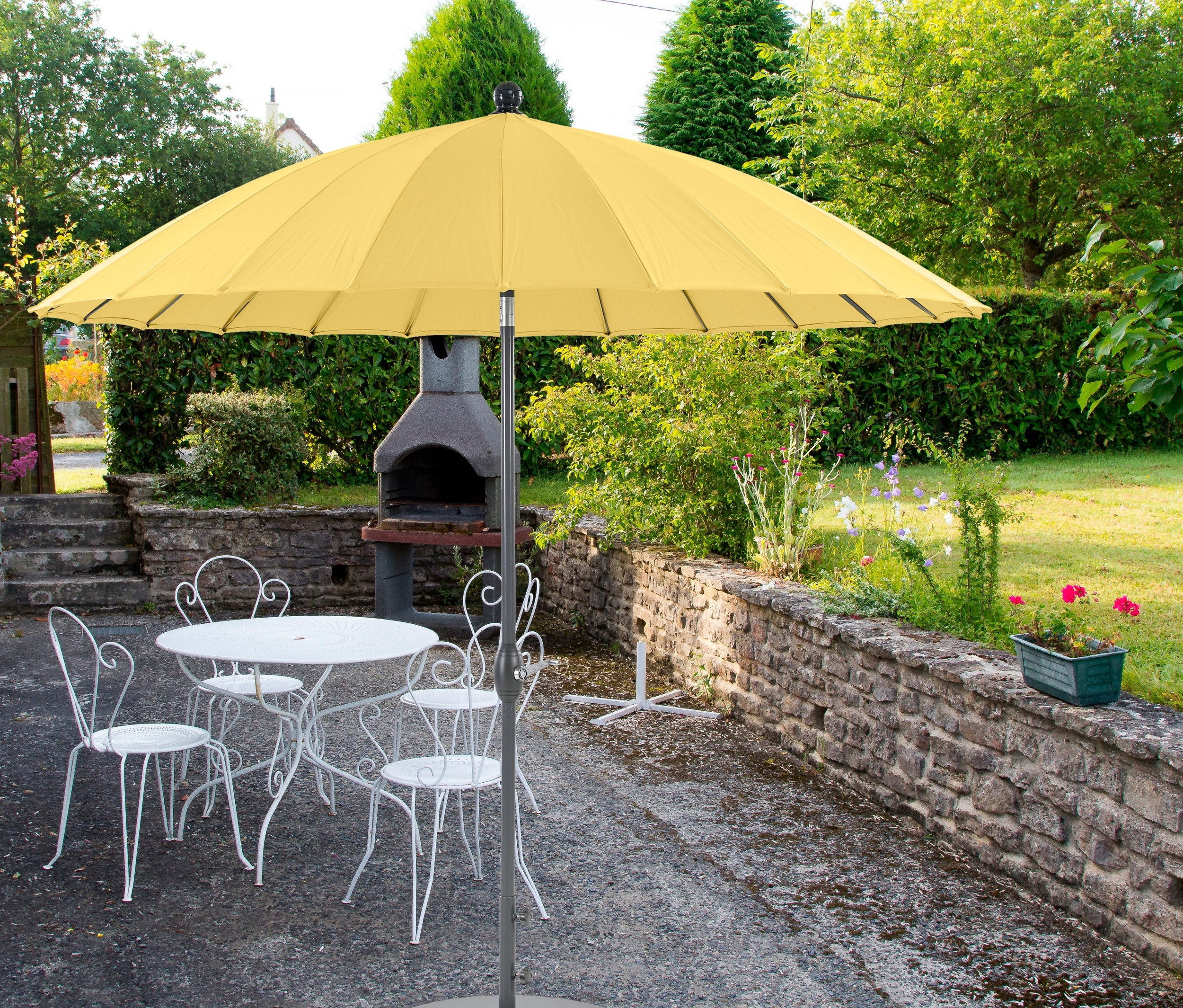 Ein gelber Leco Aluminium-Sonnenschirm »Shanghai« mit ca. 270 cm Durchmesser steht über einem weißen Metalltisch mit Stühlen auf einer Terrasse.