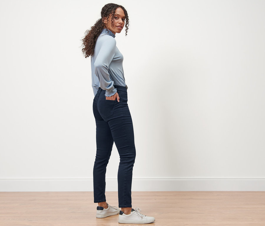 Eine Frau steht seitlich und posiert in dunkelblauen Treggings – Fit »Nelly«.