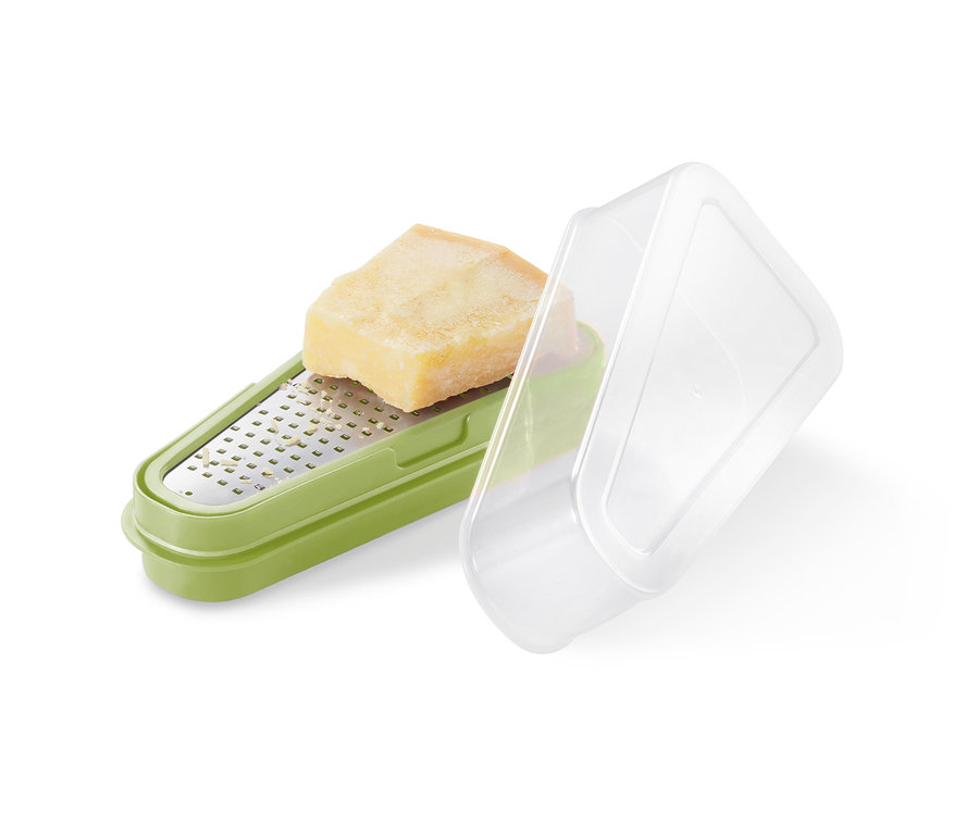 Ein Stück Parmesan liegt auf einer grünen 2-in-1-Parmesanreibe mit transparentem Deckel