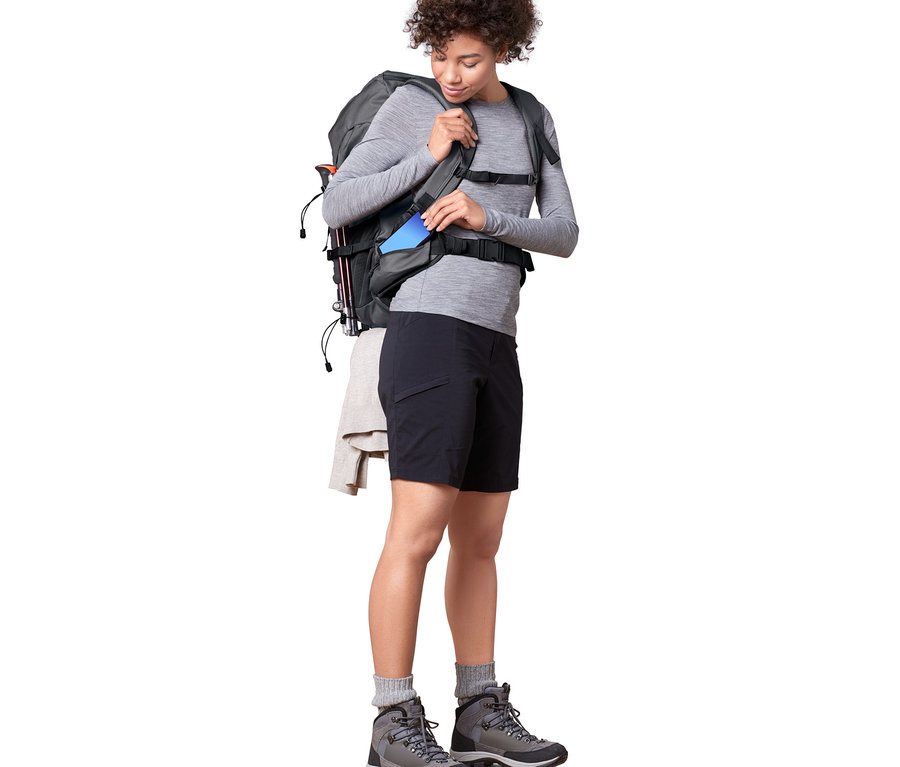 Frau steckt blaues Handy in Wander-Rucksack, 40 l.