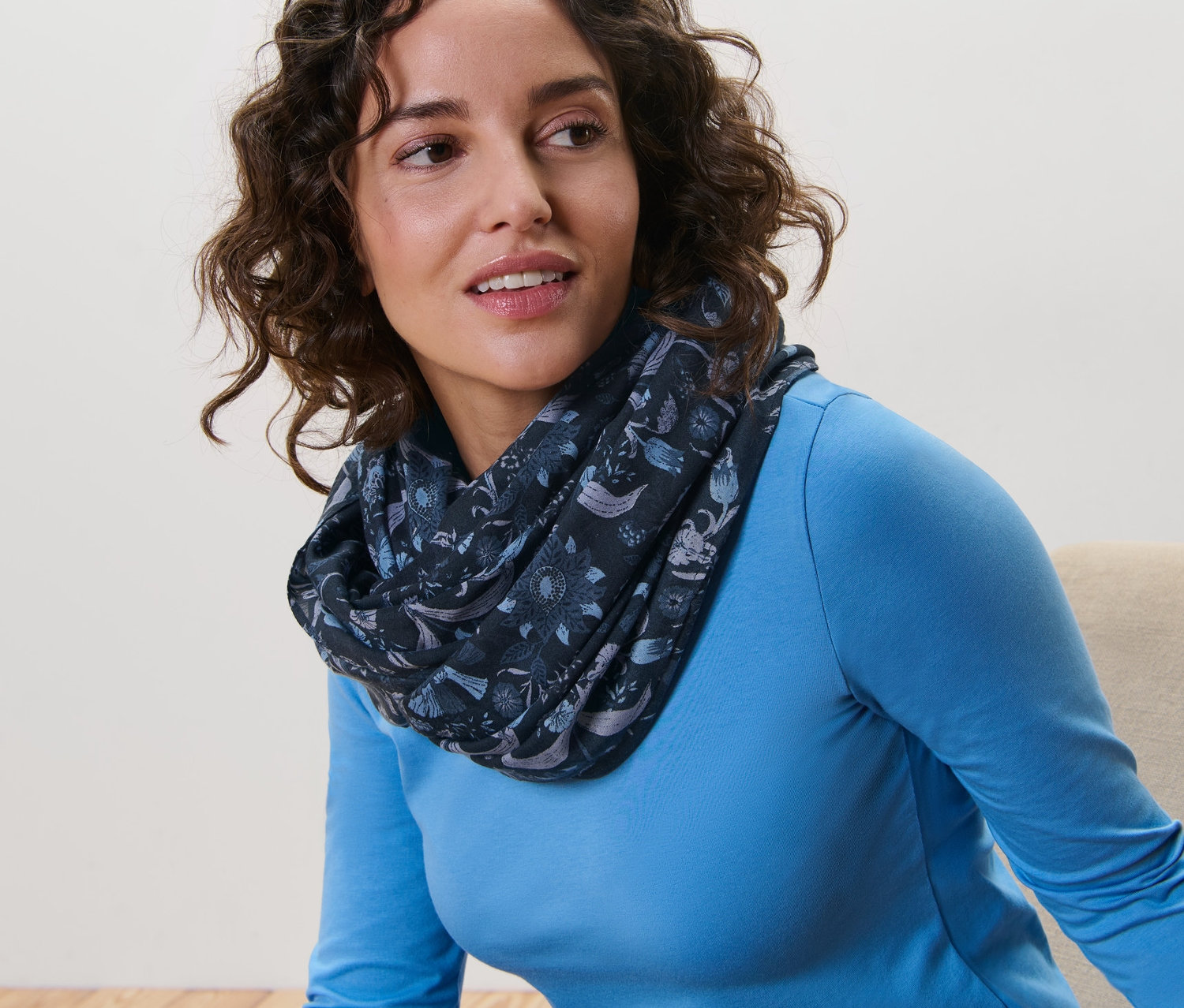 Frau mit braunen Haaren trägt einen bedruckten Loop-Schal.