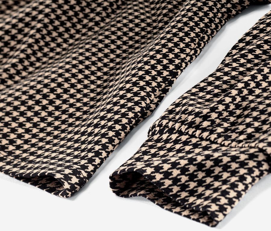 Detailansicht eines bedruckten Blusenshirts mit V-Ausschnitt im Hahnentrittmuster.