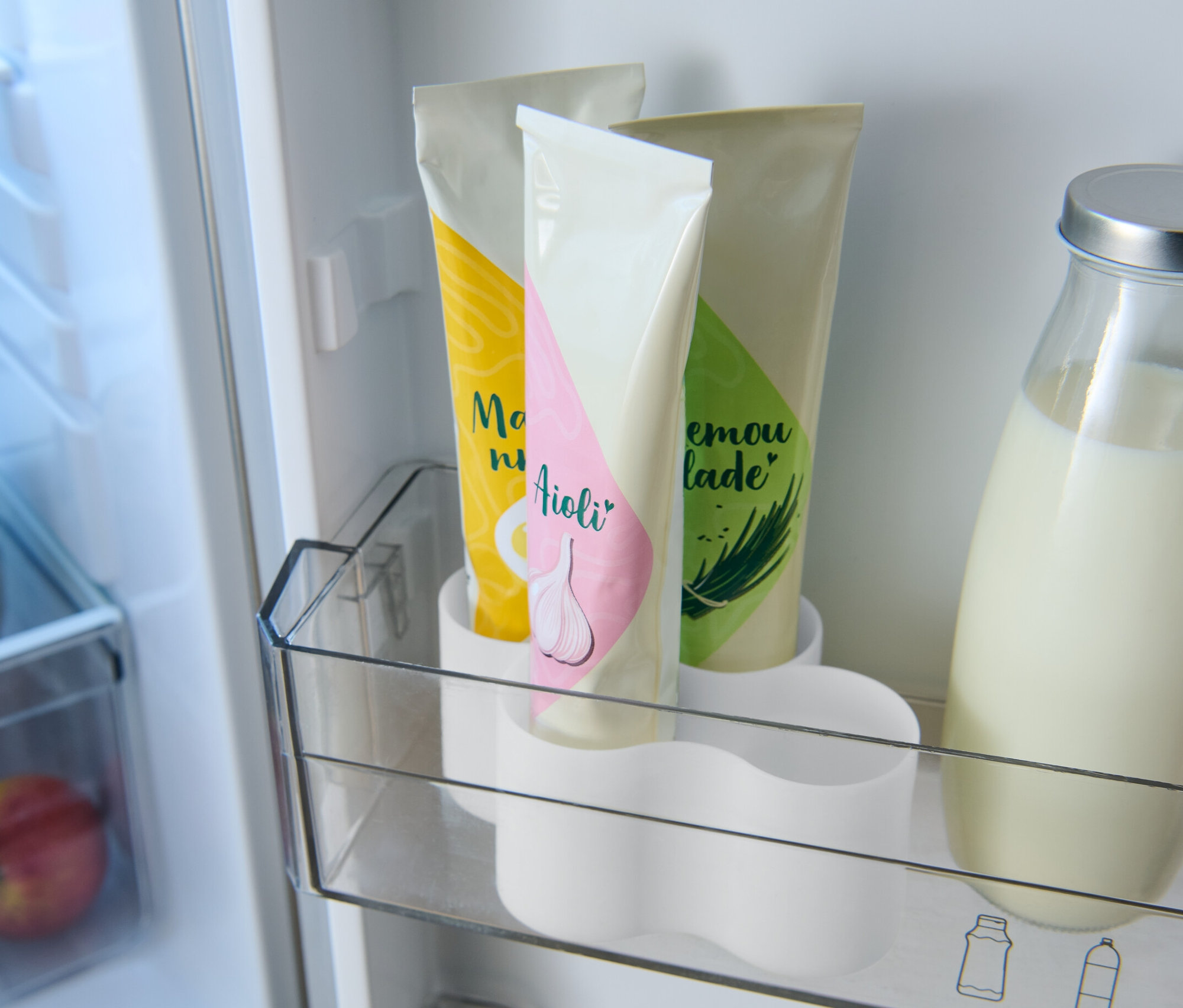 Im Kühlschrank befinden sich drei Tuben in einem Tubenhalter und eine Glasflasche mit Milch.