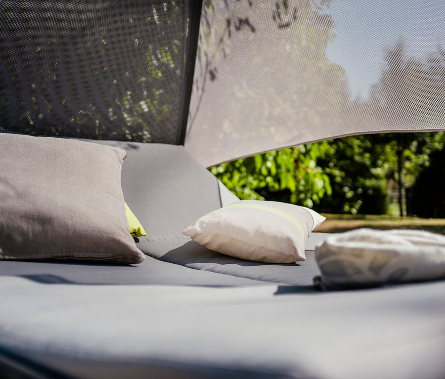 Graues Sonnenbett mit Kissen und Sonnendach.