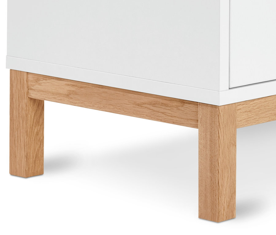 Detail einer weißen, flachen Kommode mit Holzfüßen.