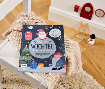 Das Buch: »Kleiner Wichtel, komm herein« liegt auf einem Pullover auf einem weißen Stuhl.