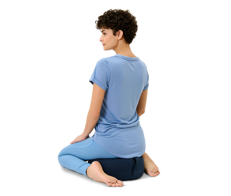 Frau sitzt auf einem Meditationskissen.