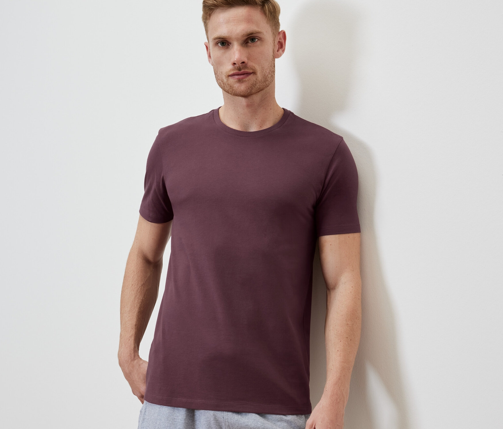 Mann trägt graues T-Shirt und graue Shorts.