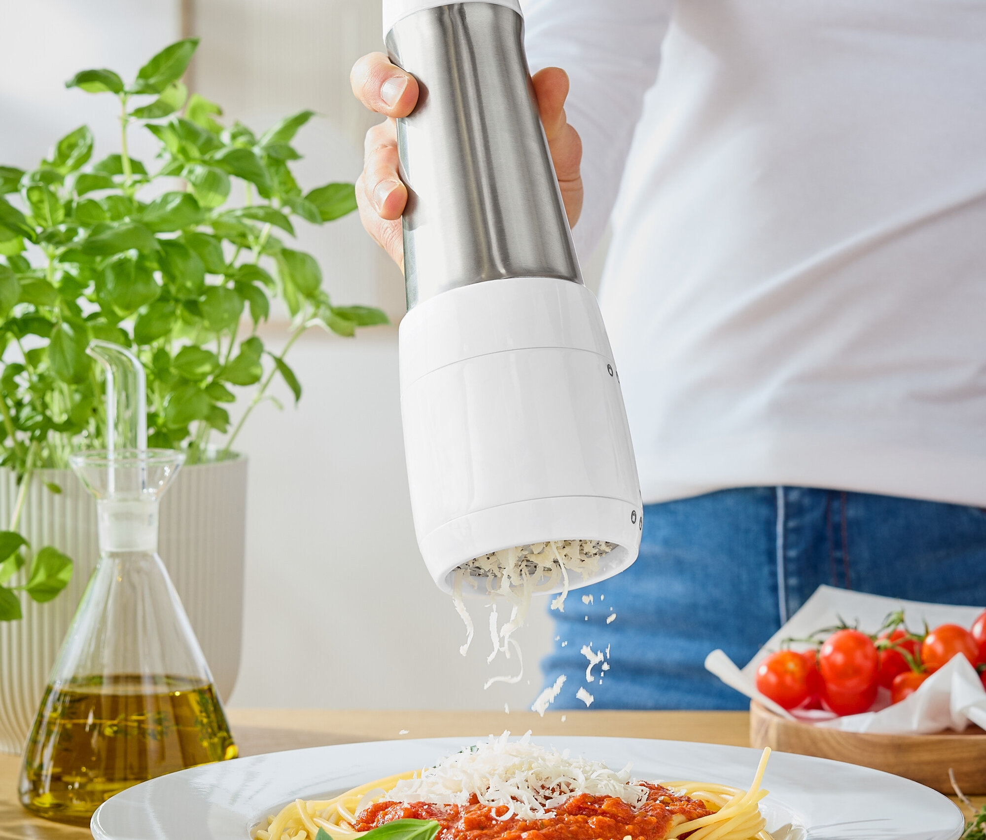 Frau reibt Käse mit einer Käsereibe auf Spaghetti mit Tomatensauce.