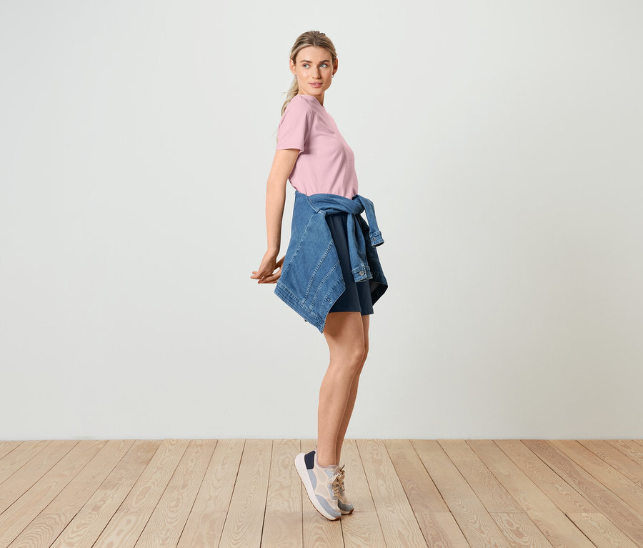 Frau posiert in Basic T-Shirt, rosé, Jeansjacke und Bermuda-Sweatshorts.