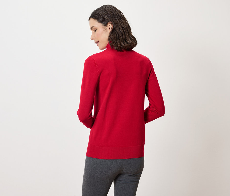 Rückansicht einer Frau mit dunklen Haaren, die einen roten Pullover und eine graue Hose trägt.