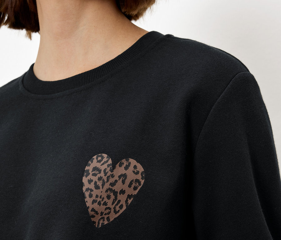 Frau trägt ein schwarzes Sweatshirt mit einem Leopardenherz.
