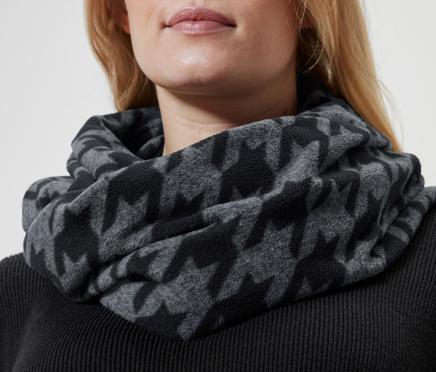 Nahaufnahme einer blonden Frau mit einem grauen Hahnentritt-Schal um den Hals und einem schwarzen Pullover.