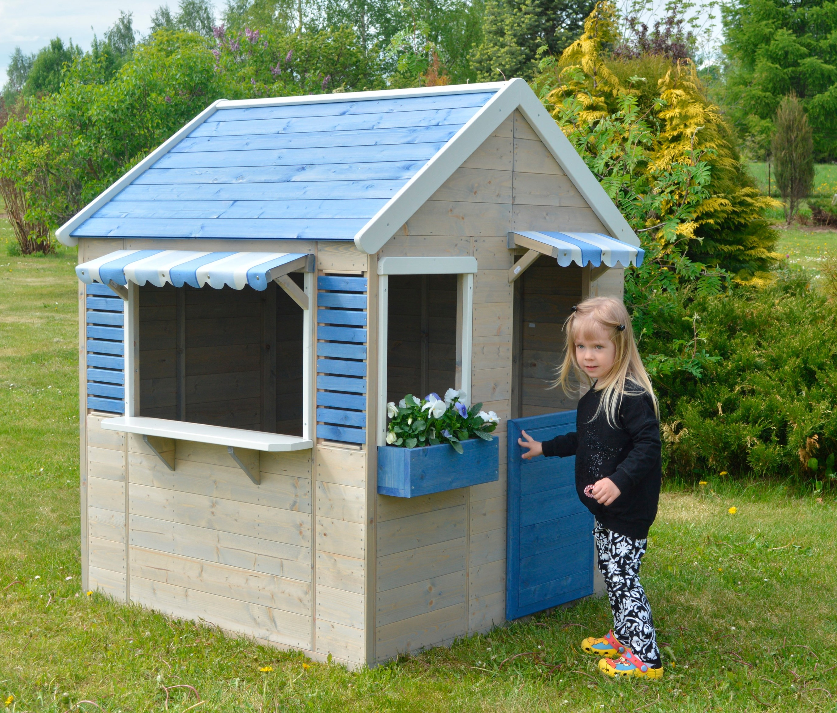 Mädchen steht vor Wendi-Spielhaus »Maritime House« im Garten.