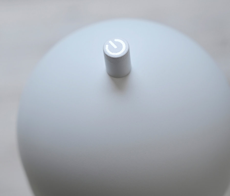 Detailansicht eines kugelförmigen, weißen Diffusors mit einem Netzschalter.