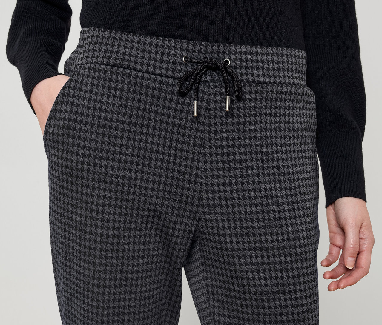Person trägt Hose mit Hahnentrittmuster und schwarzem Kordelzug.