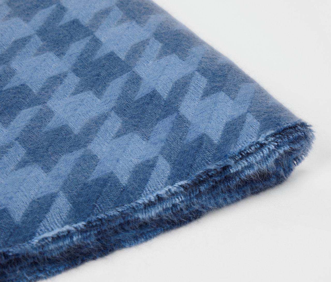 Detailaufnahme eines blauen Stoffes mit Hahnentrittmuster.