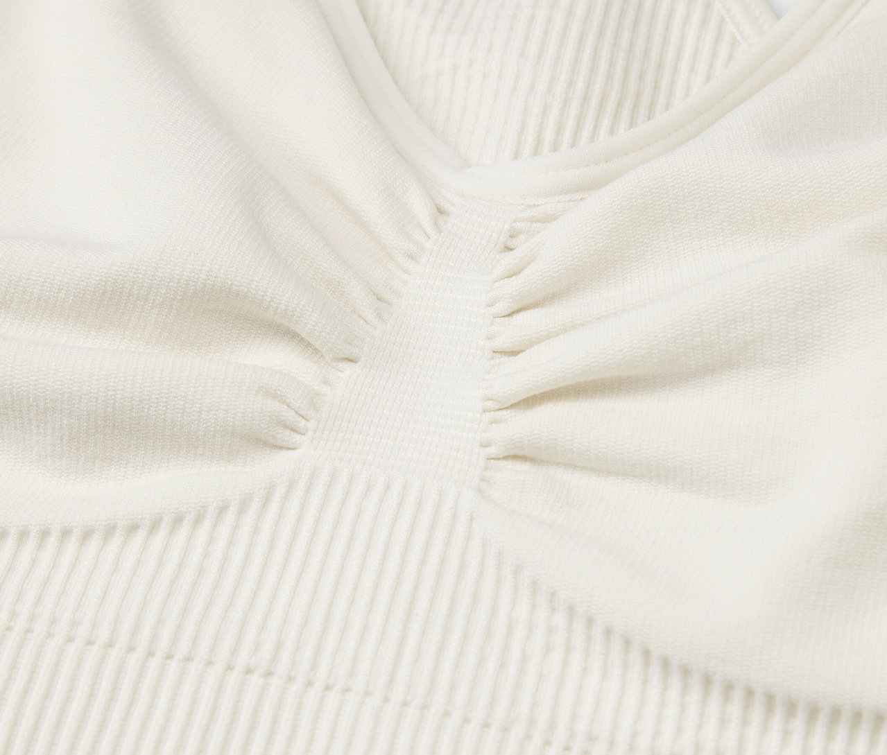 Detailaufnahme eines strukturierten, cremefarbenen Sportoberteils.