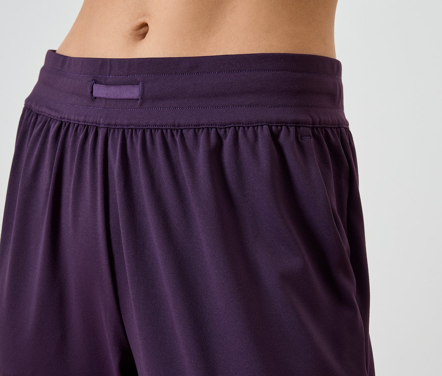 Detailaufnahme einer violetten Damenhose mit elastischem Bund und Taschen.