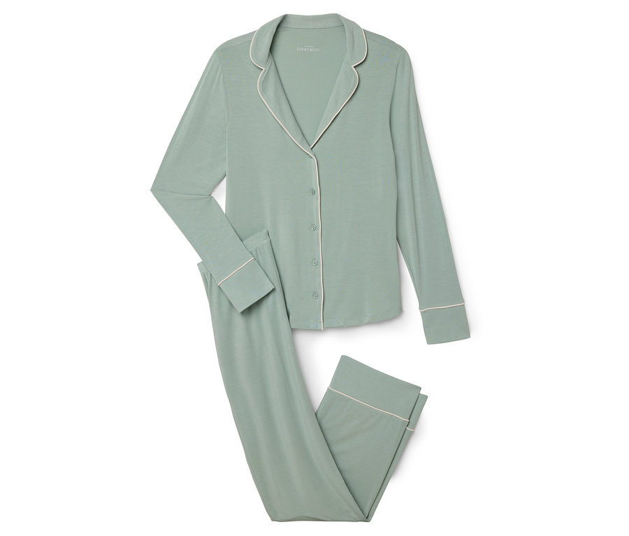 Ein grüner Pyjama mit weißer Paspelierung liegt auf einem weißen Hintergrund.