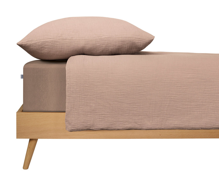 Bett mit hellbraunem Laken und Kissen auf einem Holzrahmen.