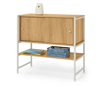 Ein Holzschrank mit einer weißen Bärenlampe darauf, darunter Bücher und eine blaue Kiste.