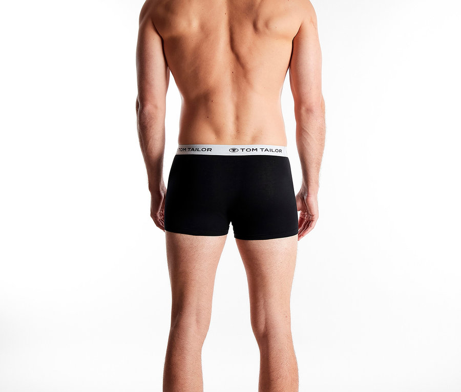 Rückansicht eines Mannes mit nacktem Oberkörper, der schwarze Boxershorts mit TOM TAILOR-Bund trägt.
