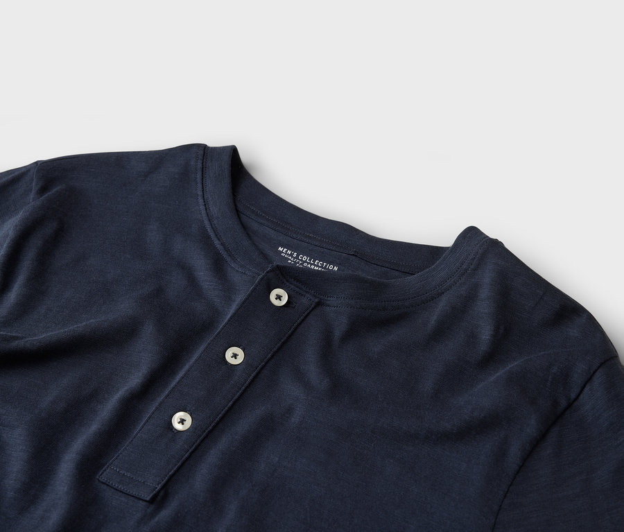 Nahaufnahme eines dunkelblauen Henley-Shirts mit drei Knöpfen.