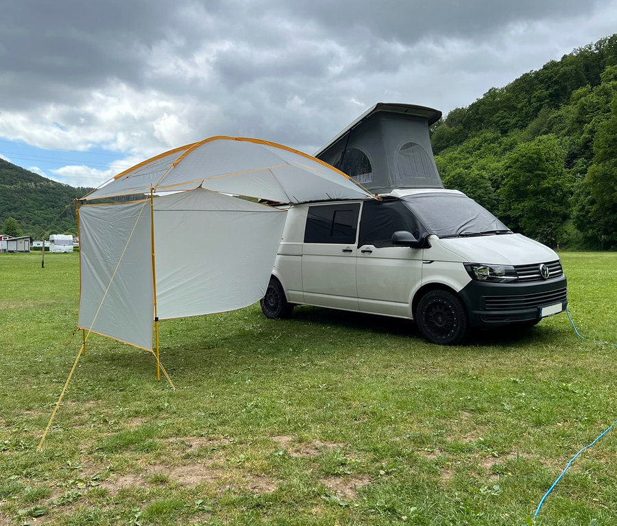 Weißer Van mit geöffnetem Dach und Tambu Sonnensegel »BASANT« auf einer Wiese.