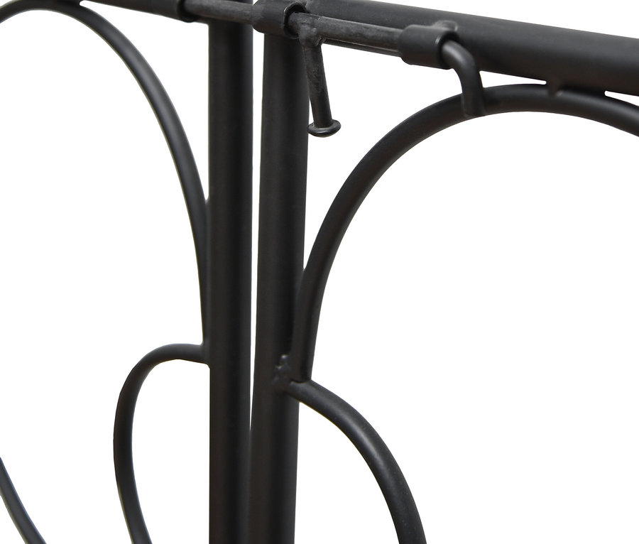 Nahaufnahme eines schwarzen Metallbettes mit herzförmigen Verzierungen und kugelförmigen Abschlüssen.