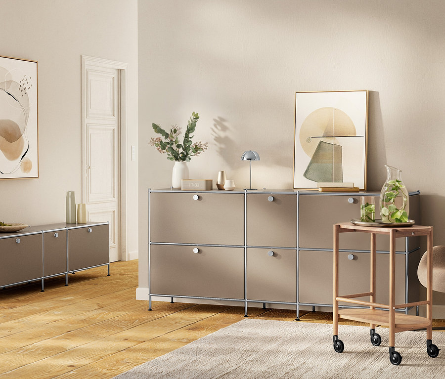Wohnzimmer mit Sideboard, Kunstwerken an der Wand und einem Servierwagen mit Getränken.