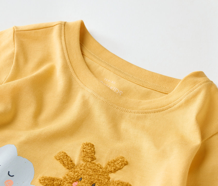 Nahaufnahme eines gelben Kinder-T-Shirts mit Wolken- und Hasenmotiv.