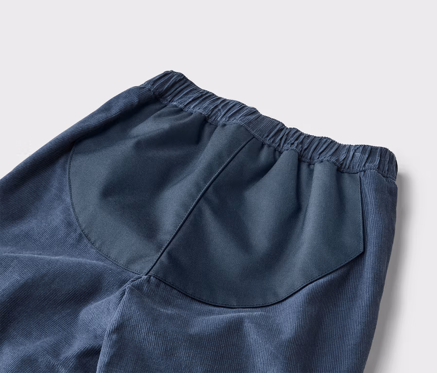 Detailaufnahme einer blauen Kordhose mit elastischem Bund und aufgesetzter Gesäßtasche.