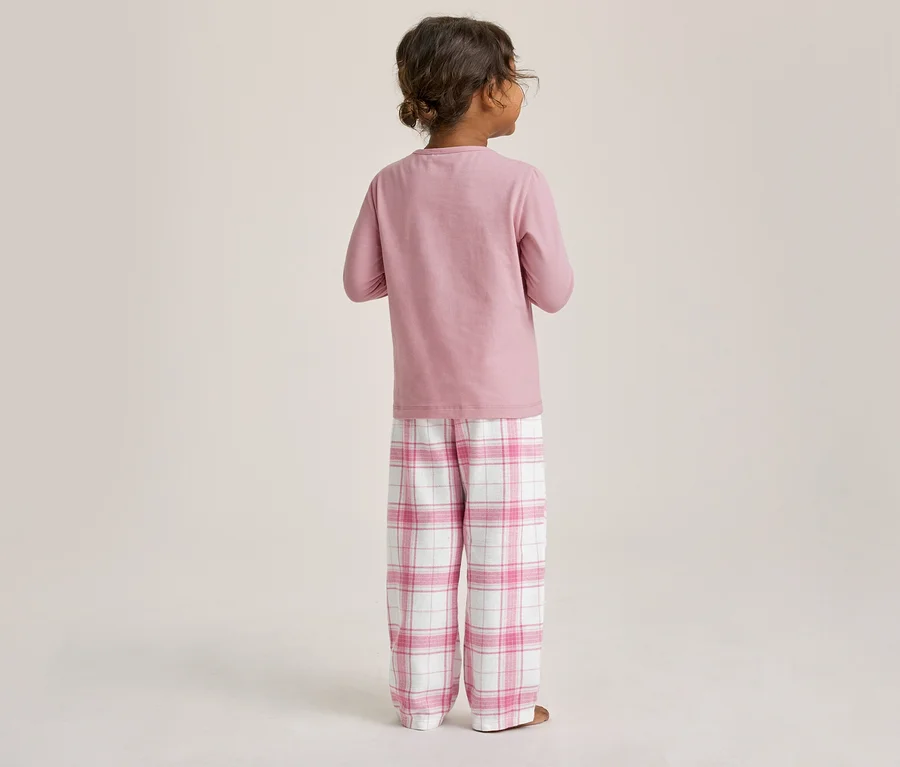 Kind von hinten, trägt einen rosa Langarm-Pyjama und eine rosa-weiß karierte Pyjamahose.