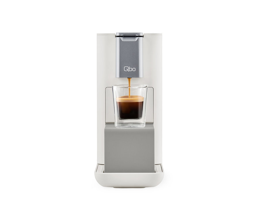 Kaffee wird aus einer Qbo ESSENTIAL Bright Sand Kaffeemaschine in ein Glas gegossen.