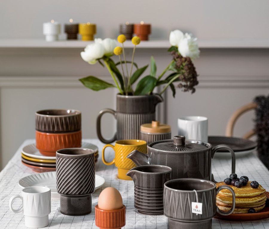 Auf einem Tisch stehen eine Teetasse, ein Krug, ein Milchkännchen und eine Teekanne.