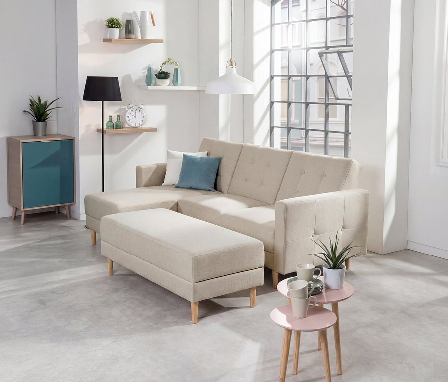 Cremefarbenes Federkern-Eckschlafsofa »Just Relax« mit Stauraumbank in einem hellen Wohnzimmer. Daneben stehen ein türkisfarbener Schrank, eine Stehlampe und zwei rosa Beistelltische.