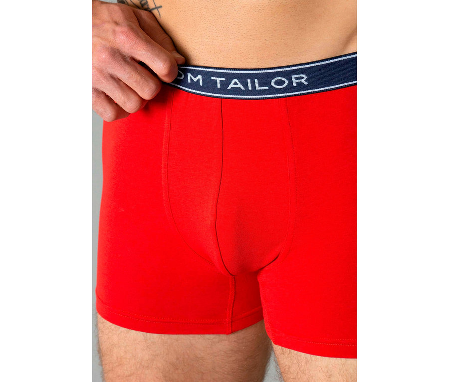Mann trägt rote Tom Tailor „Buffer“ Slipboxer; eine Hand zieht den marineblauen Bund hoch.