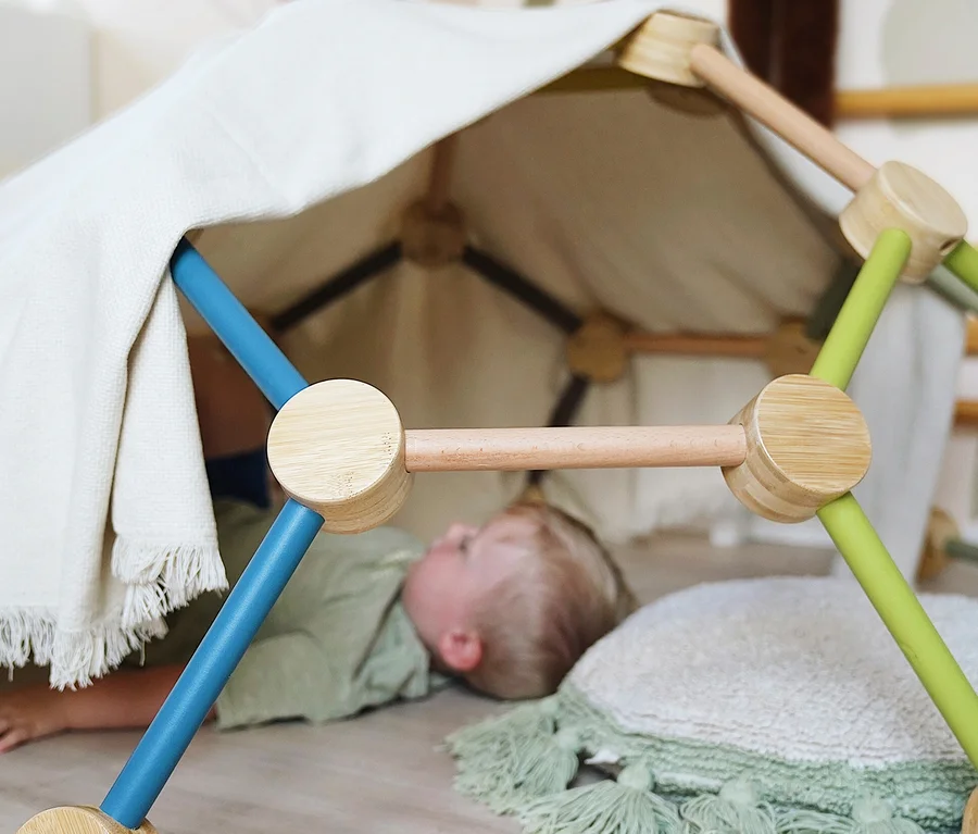 Ein Junge liegt unter der mit einem Tuch bedeckten small foot Kletterkuppel »Adventure«.