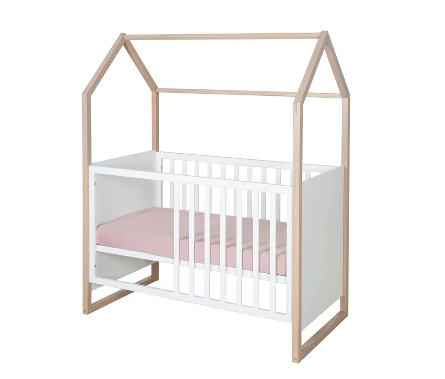 Weißes Babybett mit naturfarbenem Hausrahmen und rosa Laken.