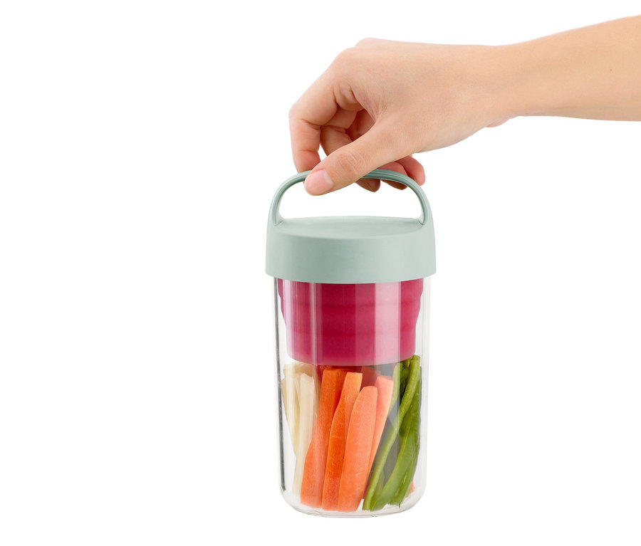 Eine Hand hält eine To-go-Lunchbox, die mit geschnittenem Gemüse gefüllt ist.